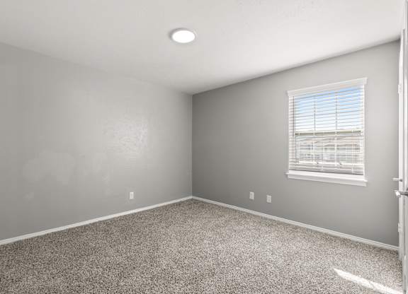 A room with a carpeted floor and a window with blinds.at The Sidney, Sherman Texas