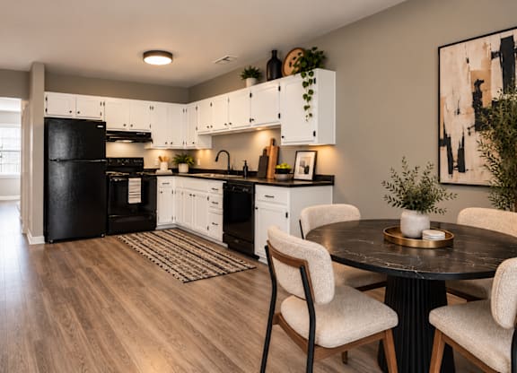 A modern kitchen with a black refrigerator and white cabinets.