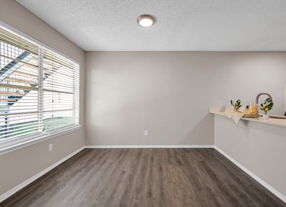 an empty living room with a large window and wood flooring