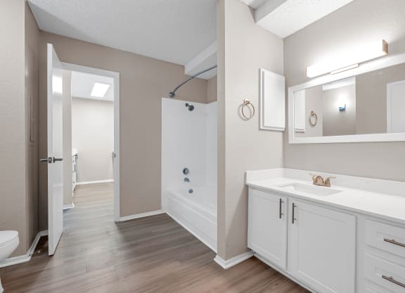 a bathroom with white cabinets and a shower and a sink