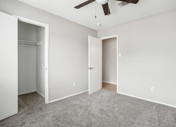an empty bedroom with a closet and a ceiling fan