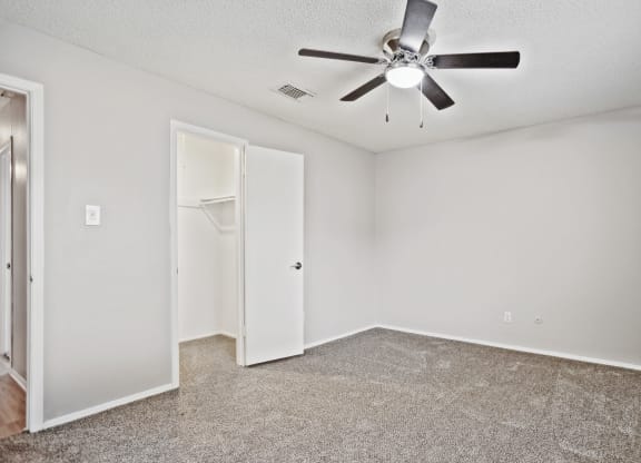 an empty room with a ceiling fan and a closet