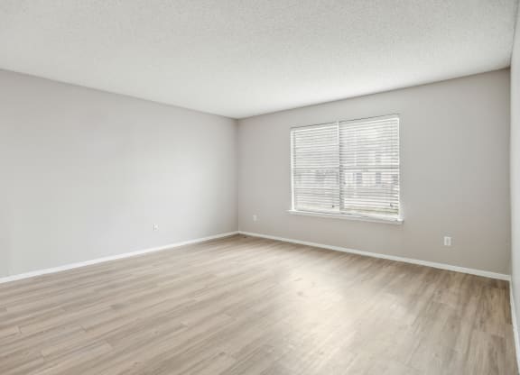 the spacious living room with wood flooring and a window