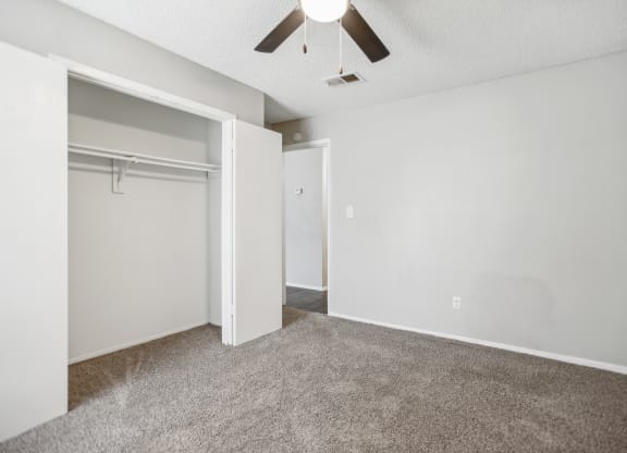 an empty living room with a closet and a ceiling fan