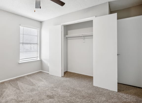an empty bedroom with a closet and a window
