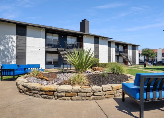 a courtyard with two blue chairs in front of a building