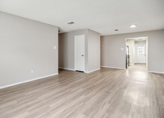 the living room and dining room of an apartment with wood floors and white walls