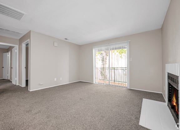 an empty living room with a fireplace and a door to a balcony