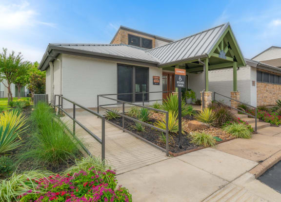 the front of a building with a porch and a walkway with plants