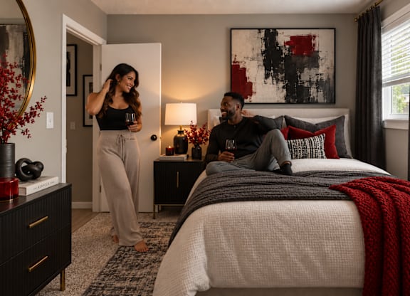 A man and woman are sitting on a bed in a bedroom.