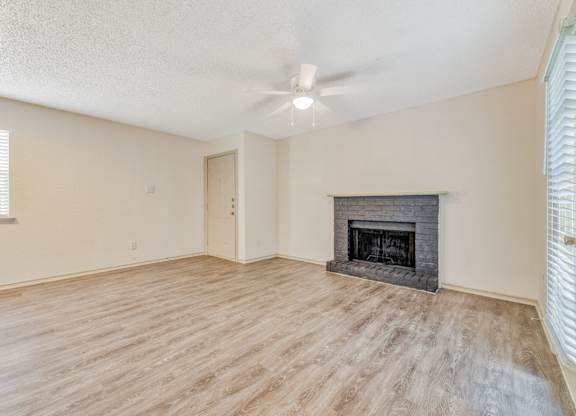 an empty living room with a fireplace and a ceiling fan