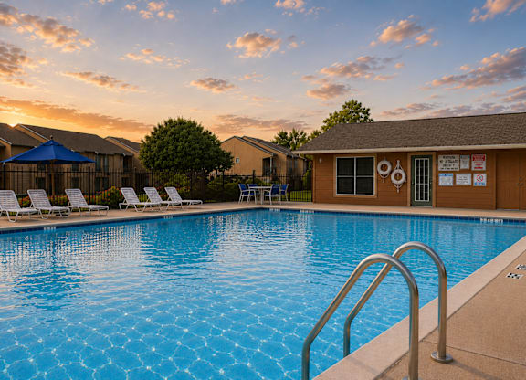 Outdoor swimming pool with lounge chairs at sunset at Ridgeview Apartments, Sherman, Texas