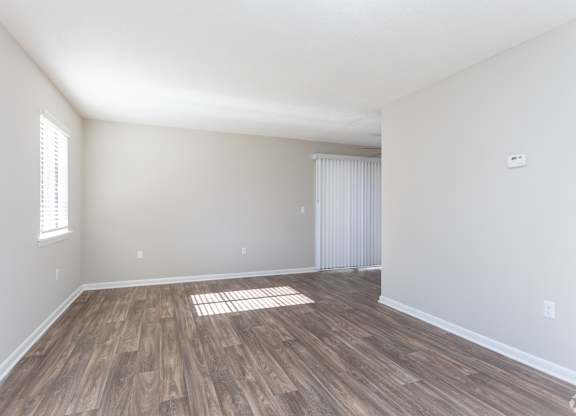 an empty living room with wood flooring and white walls at Rosen at North Hills, Raleigh