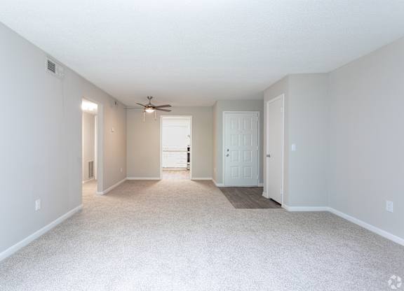 an empty living room with white carpet and a ceiling fan at Rosen at North Hills, Raleigh, NC