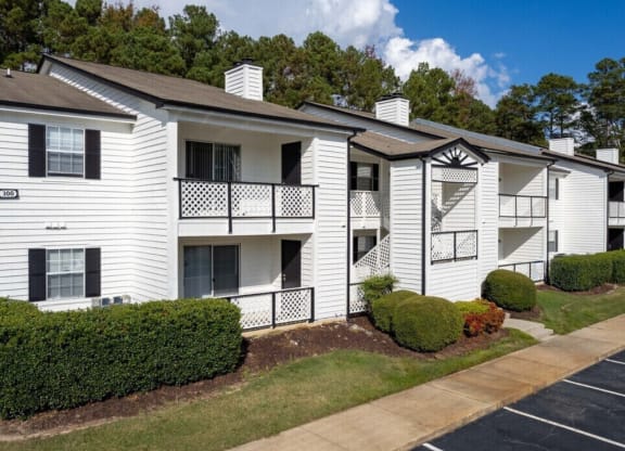an apartment building with white siding and a sidewalk