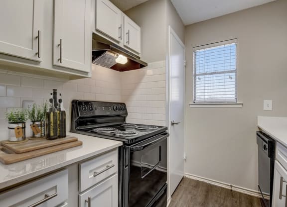 an empty kitchen with white cabinets and a black stove and oven