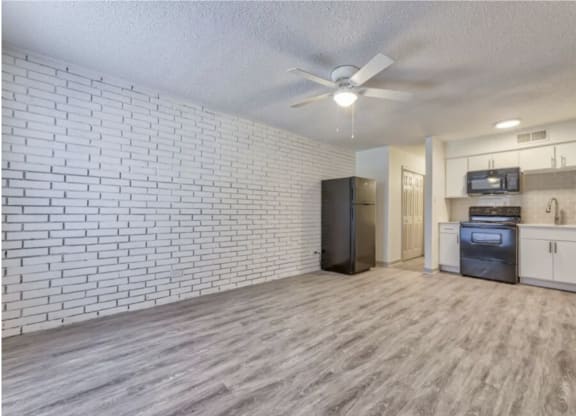 an open living room with a kitchen and a ceiling fan