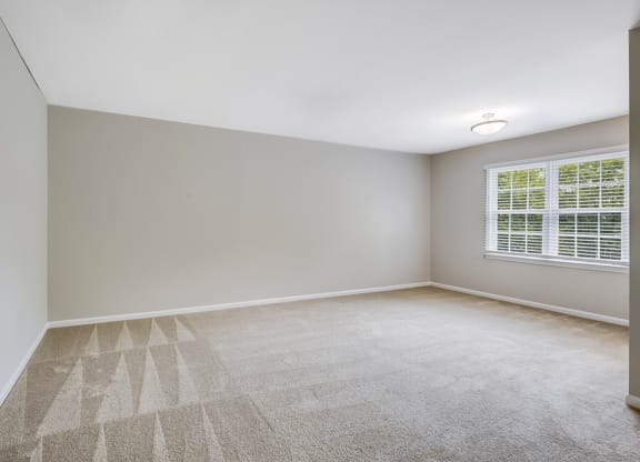 an empty room with a window and white walls