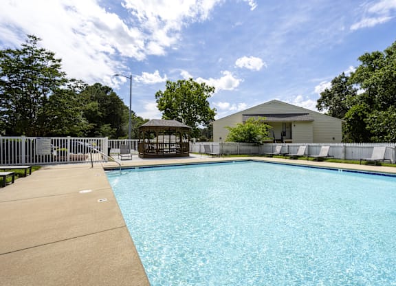 A large swimming pool surrounded by a fence and a building in the background.