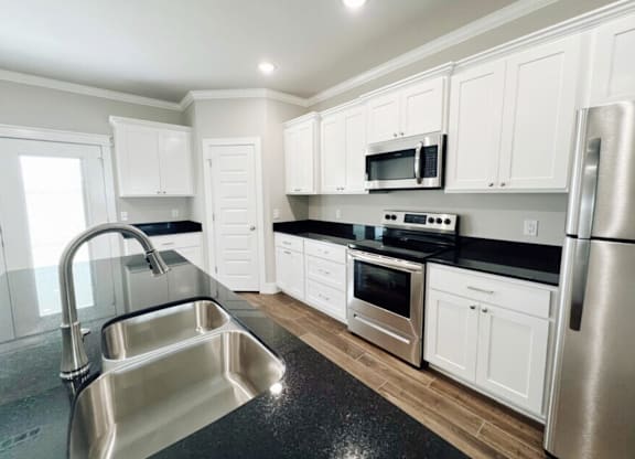 A kitchen with white cabinets and stainless steel appliances at Cedar Crest Apartments, Arkansas