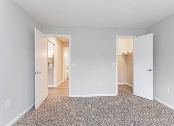 an empty room with two doors and a carpeted floor