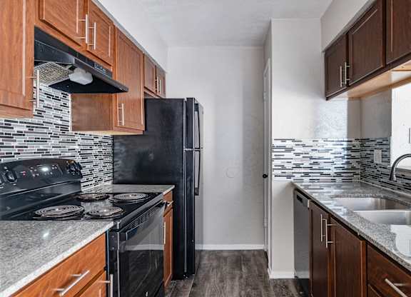 Galley kitchen with black appliances and granite counters at Ridgeview Apartments, Sherman, Texas