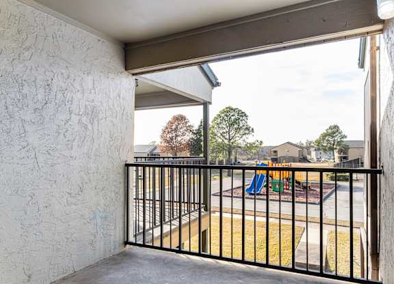 Private balcony overlooking playground and grassy courtyard at Ridgeview Apartments, Texas