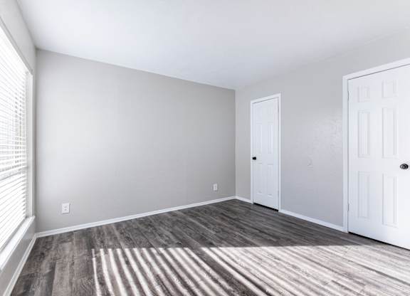 Empty bedroom with white doors and window blinds at Ridgeview Apartments, Texas, 75092