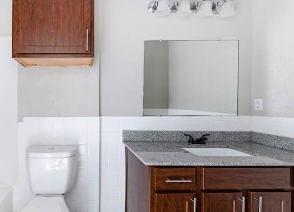 Bathroom vanity with granite countertop and mirrored medicine cabinet at Ridgeview Apartments, Sherman, TX
