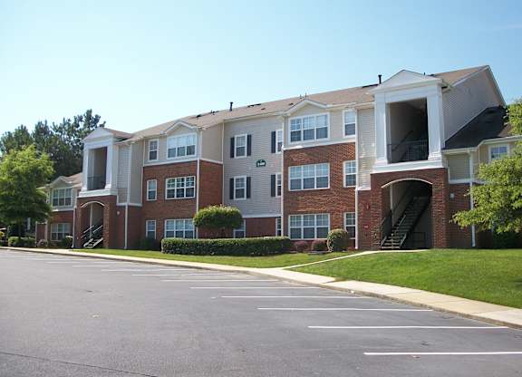 Apartment building with a parking lot in front.