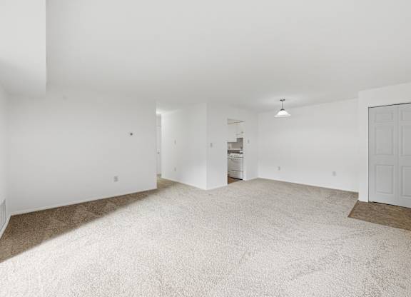 A large, empty room with a carpeted floor and white walls.