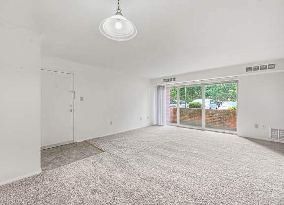 A room with a carpeted floor and a sliding glass door.