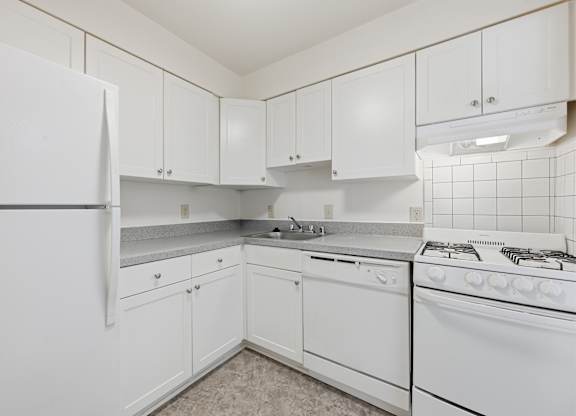 A white kitchen with a stove and a refrigerator.