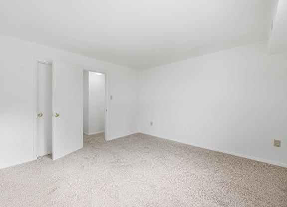 A white room with carpeted floor and two doors.