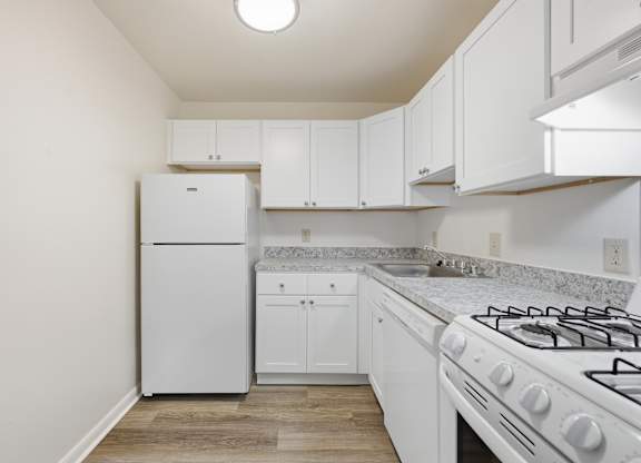 A white kitchen with a stove, refrigerator, and cabinets.