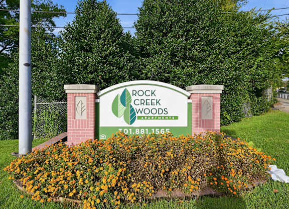 A sign for Rock Creek Woods with a phone number on it.