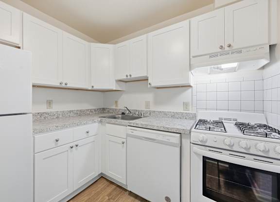 A white kitchen with a stove, oven, and cabinets.