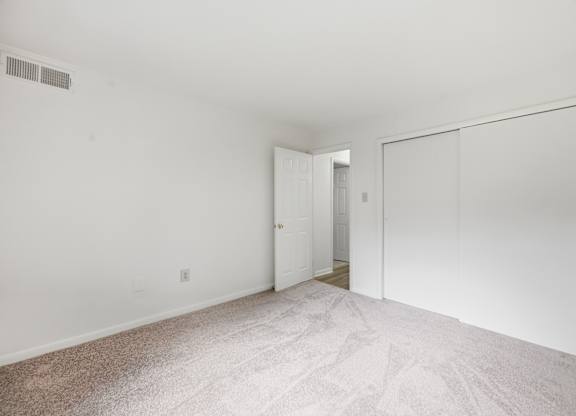A white room with a carpeted floor and a door on the right.