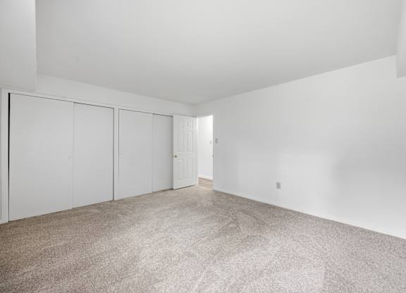 A large empty room with carpeted floor and white walls.