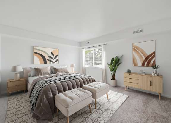 A bedroom with a large bed, a bench, and a painting on the wall.