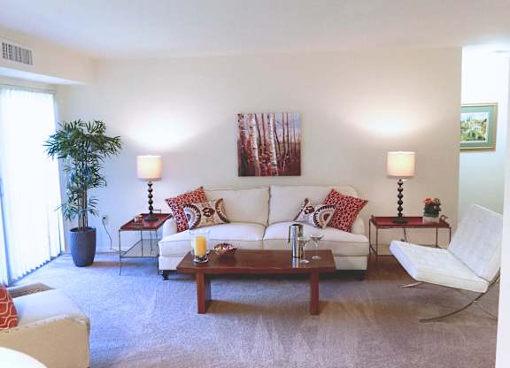 A living room with a white couch, a coffee table, and a lamp.