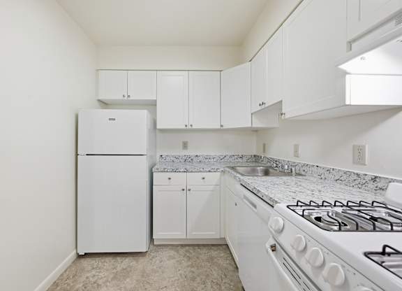 A white kitchen with a stove, refrigerator, and cabinets.
