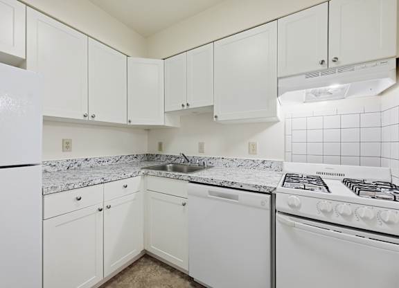 A white kitchen with a refrigerator, stove, and cabinets.