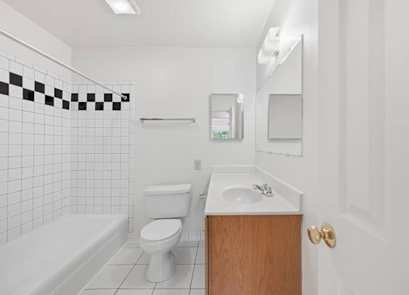 A white bathroom with a toilet, sink, and bathtub.