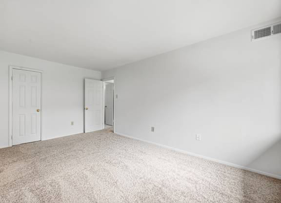 A room with carpeted floor and two doors.