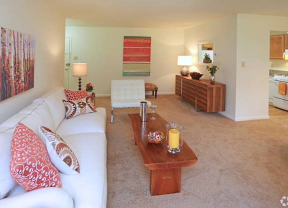 A living room with a white couch and a painting on the wall.