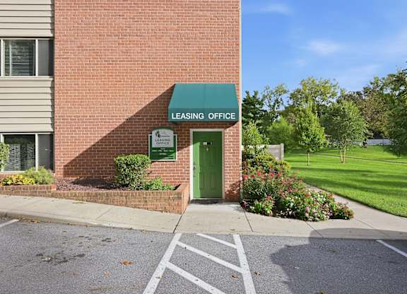 A brick building with a green door and a sign that says Leasing Office.