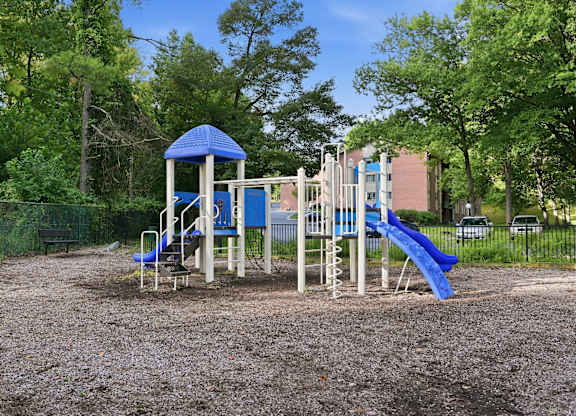 A playground with a blue slide and a wooden structure.