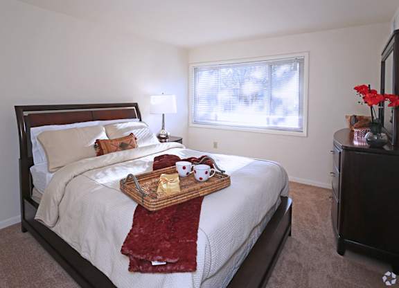 A bedroom with a bed, nightstand, and window.