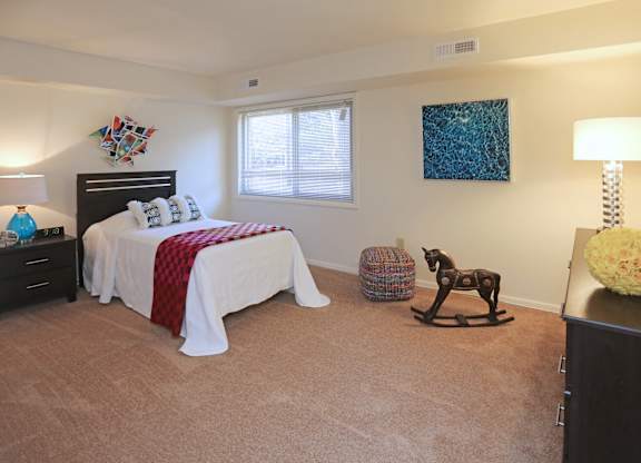 bedroom with a bed, a rocking horse, and a lamp.
